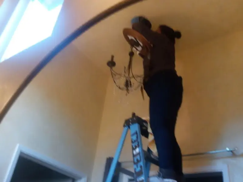 Electrician installing a chandelier in a Poteau residence